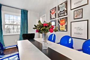 a room with a table and blue chairs and a vase with flowers at Stay Golden 1: Chic Modern-Victorian City View in Pittsburgh