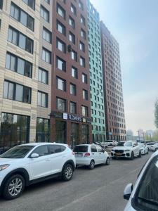 a parking lot with cars parked in front of tall buildings at Уютная квартира вблизи Байтерека in Astana