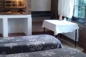 a room with two beds and a table and a piano at Alojamiento Amancay in Trenque Lauquen