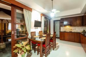 Sanur Beach Villa - 3BR Private Pool في سانور: مطبخ وغرفة طعام مع طاولة وكراسي