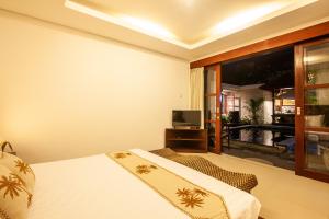 sypialnia z łóżkiem, telewizorem i oknem w obiekcie Sanur Beach Villa - 3BR Private Pool w mieście Sanur