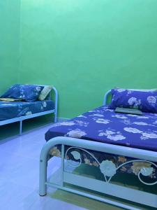 twee bedden in een kamer met blauwe en groene muren bij Sri Aman Homestay in Jitra