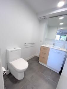 a white bathroom with a toilet and a sink at Unit 3 - Manly Boutique Apartments in Brisbane