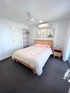 a bedroom with a bed with a pink comforter at Unit 3 - Manly Boutique Apartments in Brisbane