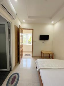 Phương Thảo Motel (phòng đơn) في فنغ تاو: غرفة نوم مع سرير وتلفزيون على الحائط