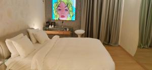 Un dormitorio con una cama blanca y una pintura en la pared en Mirada Hotel, en Atenas