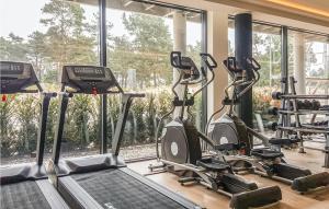 - une salle de sport avec tapis de course et vélos elliptiques devant une fenêtre dans l'établissement Prora Solitaire Avida Loft13, à Binz