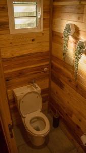 a bathroom with a toilet in a wooden wall at Ti CASE GERMAINE in Entre-Deux