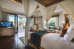 a bedroom with a large bed with a television in it at Kuwarasan A Pramana Experience in Ubud