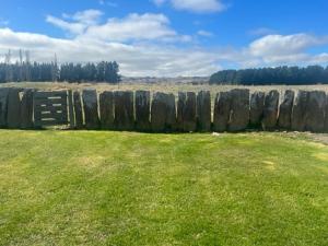 a large stone wall in a field with green grass at Taieri Bank Cottage - Middlemarch, Otago in Middlemarch