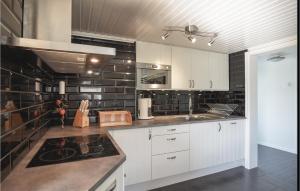 a kitchen with white cabinets and black brick walls at 5 Bedroom Amazing Home In Bjrketorp in Björketorp