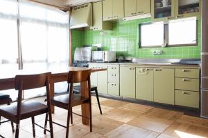 a kitchen with a wooden table and green tiles at 【湯布院の山小屋】サンクラウド・ヒュッテ in Yufuin