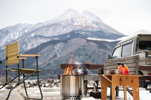 a grill and a table with a campfire and a mountain at 【湯布院の山小屋】サンクラウド・ヒュッテ in Yufuin