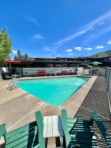 uma piscina com cadeiras verdes e um edifício em Timbers INN and Suites em Ashland