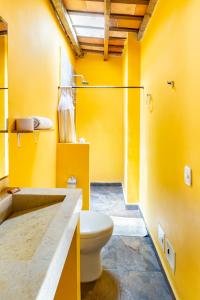 a yellow bathroom with a toilet and a shower at Gagaka Rua hostel in Santa Marta