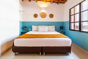 a bedroom with a bed with blue walls and windows at Gagaka Rua hostel in Santa Marta