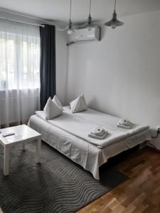 a white bedroom with a bed and a table at Apartament Alina in Deva