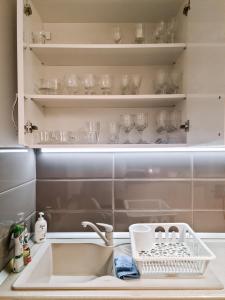 a kitchen counter with a sink and glasses on shelves at Apartament Alina in Deva