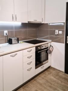 a kitchen with white cabinets and a stove top oven at Apartament Alina in Deva