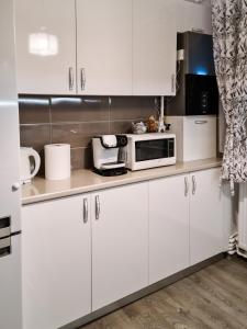 a kitchen with white cabinets and a microwave at Apartament Alina in Deva