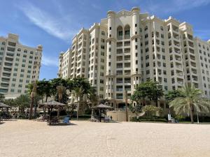 un gran edificio blanco con sombrillas delante en Al Dabas Beach Views, 3BD Sleeps 6, Beachfront Beach & Pool Access en Dubái