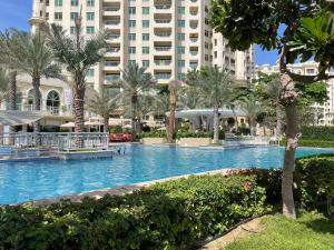 une piscine bordée de palmiers et un grand bâtiment dans l'établissement Al Dabas Beach Views, 3BD Sleeps 6, Beachfront Beach & Pool Access, à Dubaï