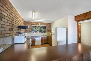 a kitchen with a white refrigerator and a brick wall at Carlaminda Peregian Beach in Peregian Beach +5 photos