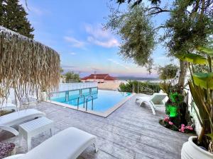 um pátio com uma piscina e cadeiras brancas em Luxury Villa San George with private pool by DadoVillas em Nydri