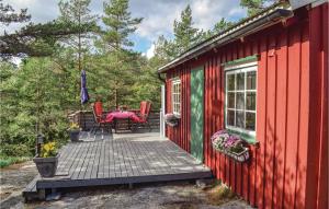 Cabaña roja y verde con mesa y sillas en la cubierta en 2 Bedroom Amazing Home In Larvik en Seierstad