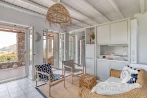 a living room with a couch and chairs and a window at Villa Vino - Cycladic Calm in Isterni
