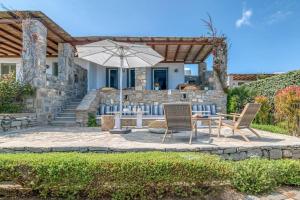 a patio with a table and chairs and an umbrella at Villa Vino - Cycladic Calm in Isterni