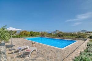 a swimming pool with two chairs and an umbrella at Villa Vino - Cycladic Calm in Isterni