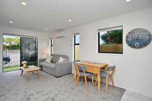 sala de estar con mesa, sofá y reloj en Sea air and Sandy Beach, beautiful 1 bed 1 bath en Christchurch