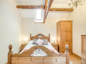 a bedroom with a wooden bed and wooden cabinets at The Stables in Bream
