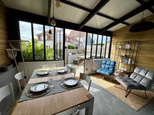 a dining room with a table and chairs and windows at Rev d’Opale in Wimereux