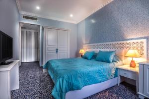 a blue bedroom with a bed and a tv at Premier Old Gates Hotel in Baku