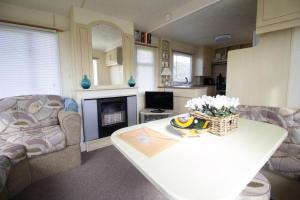 sala de estar con sofá y mesa en Lovely 4 Berth Caravan For Hire At Sunnydale Holiday Park Ref 35225kc, en Louth