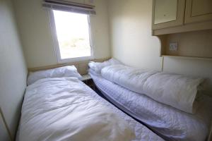 - 2 lits dans une petite chambre avec fenêtre dans l'établissement Lovely 4 Berth Caravan For Hire At Sunnydale Holiday Park Ref 35225kc, à Louth