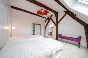 - une chambre avec 2 lits et un banc pourpre dans l'établissement Les Mansardes : Duplex champenois typique et cosy, à Ay