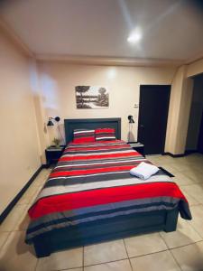 a bedroom with a large bed with red and blue stripes at Paradise Comfort in Koror
