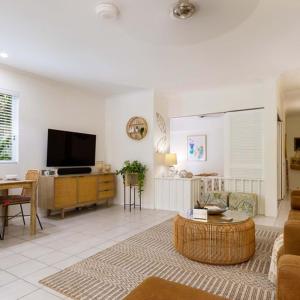 a living room with a couch and a tv at Oasis Luxe on Macrossan Street - Stylish Residence in Port Douglas