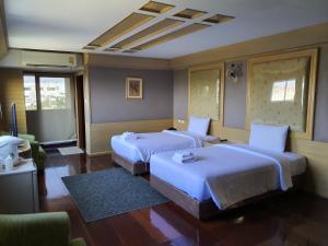 a hotel room with two beds and a television at Pearl Resort & Hotel in Nonthaburi