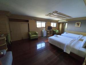 a hotel room with two beds and a chair at Pearl Resort & Hotel in Nonthaburi