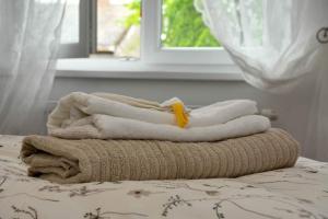 - une pile de serviettes sur un lit avec une fenêtre dans l'établissement Apartman Harmony, à Sombor