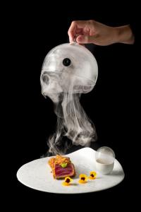 a person with a smoke head and a plate of food at Resort Miramonti in Forte dei Marmi