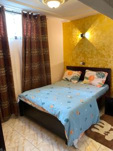 a bedroom with a bed with a yellow wall at N-E Studio meublé 2 in Douala