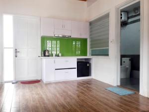 a kitchen with green and white cabinets and a wooden floor at Hồng Dương Villa Homestay - phòng đôi view sông Hương trung tâm thành phố #101 in Hue