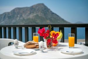 a table with a breakfast of eggs and bread and flowers at Pelagos Seafront Accommodation - Maria in Myrties