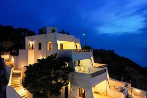 a white building with stairs leading to the ocean at night at Pelagos Seafront Accommodation - Maria in Myrties