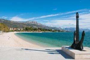 una statua seduta su una spiaggia vicino all'acqua di Studio Apartment Kastel Star a Kaštela (Castelli)